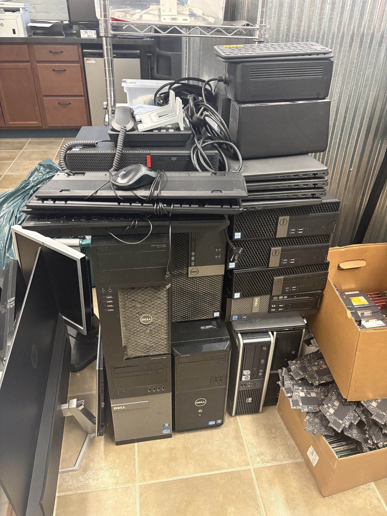 School stock room with retired Dell desktops, monitors, cables, and loose computer boards